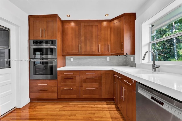 kitchen featuring decorative backsplash, sink, light wood-type flooring, and stainless steel appliances