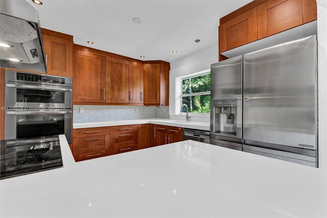 1431 Ancona Ave, Coral Gables, FL 33146 - kitchen featuring appliances with stainless steel finishes, light countertops, decorative backsplash, a sink, and brown cabinetry