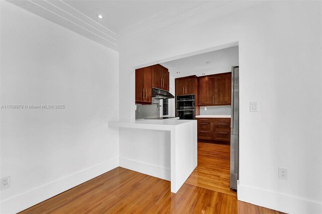 1431 Ancona Ave, Coral Gables, FL 33146 - kitchen featuring under cabinet range hood, light countertops, decorative backsplash, light wood-style floors, and baseboards