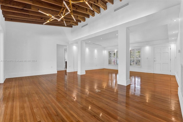 unfurnished living room featuring beamed ceiling, hardwood / wood-style flooring, and high vaulted ceiling