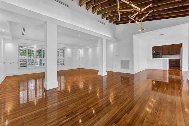 1431 Ancona Ave, Coral Gables, FL 33146 - unfurnished living room featuring ornate columns, wood finished floors, baseboards, and a towering ceiling