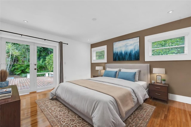 bedroom with access to exterior, hardwood / wood-style floors, and multiple windows