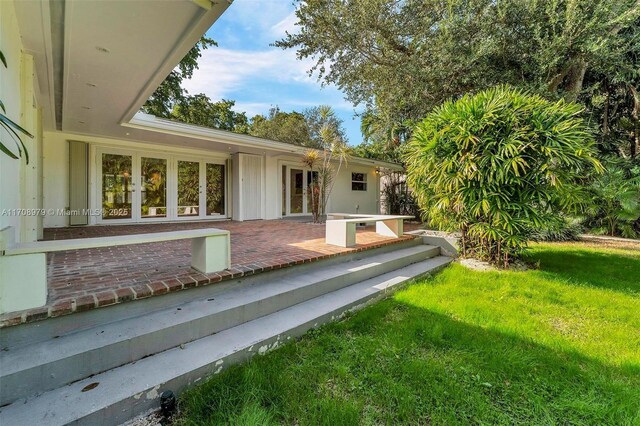 1431 Ancona Ave, Coral Gables, FL 33146 - view of exterior entry with a lawn, french doors, and a patio area