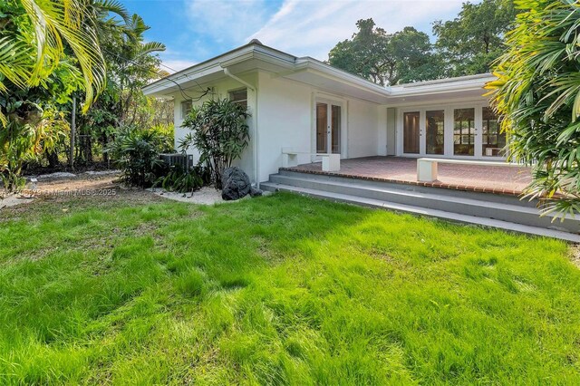 1431 Ancona Ave, Coral Gables, FL 33146 - back of house with french doors, stucco siding, a lawn, and central AC unit