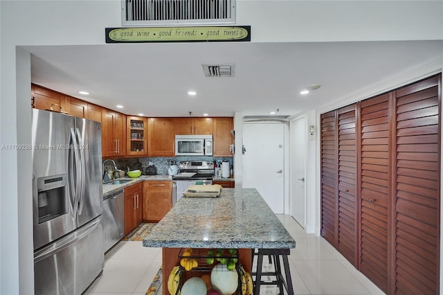 kitchen featuring a center island, light tile patterned floors, backsplash, and appliances with stainless steel finishes