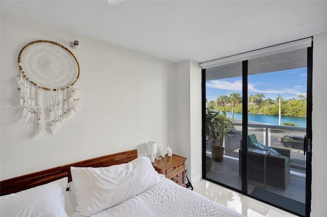 bedroom featuring floor to ceiling windows, a water view, and access to outside