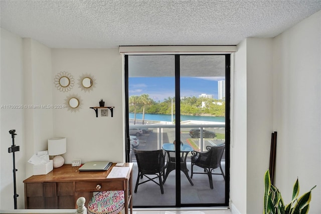 interior space with a textured ceiling, a water view, and expansive windows