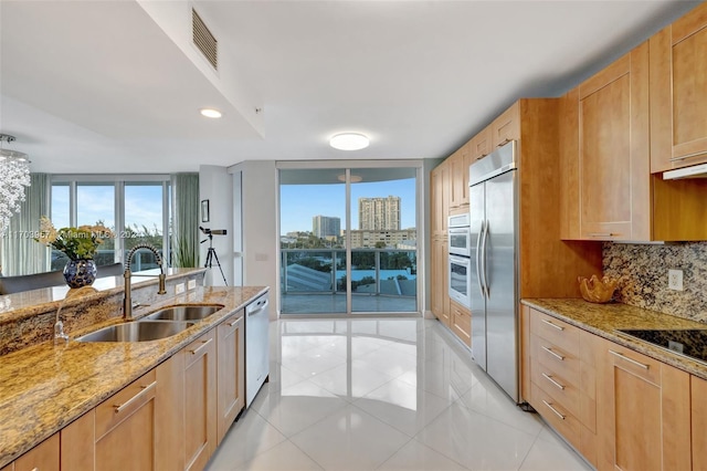 kitchen with sink, light stone counters, decorative backsplash, light tile patterned floors, and appliances with stainless steel finishes