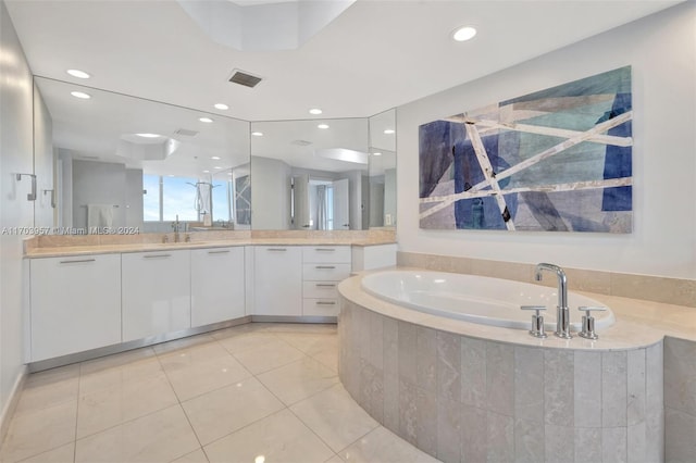 bathroom with tile patterned flooring, vanity, and a relaxing tiled tub