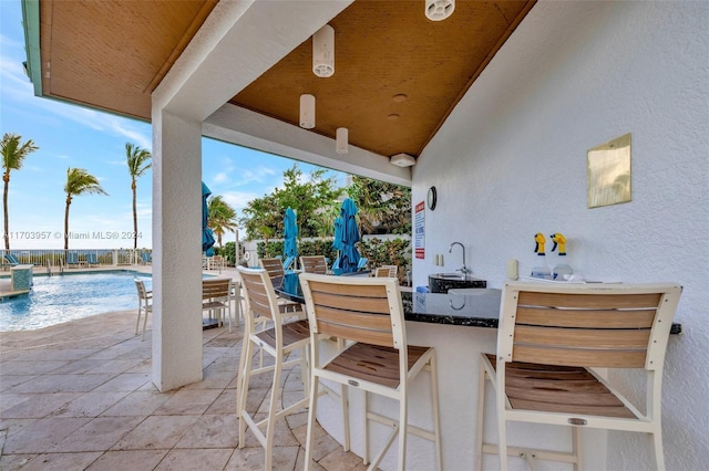 view of patio featuring a water view, a community pool, and a bar