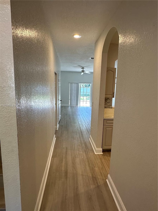 corridor with hardwood / wood-style floors and a textured ceiling