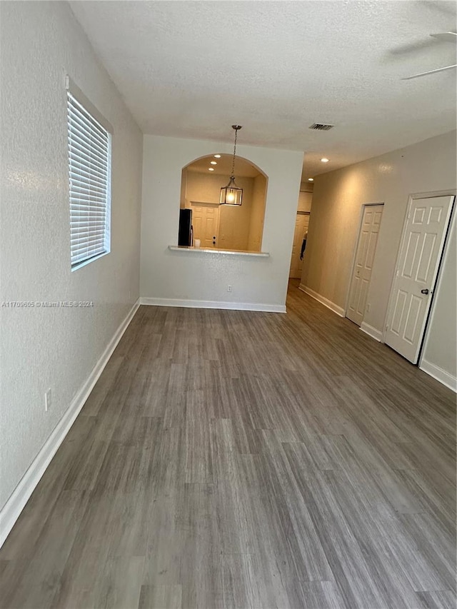 unfurnished living room featuring a textured ceiling, ceiling fan, and dark wood-type flooring