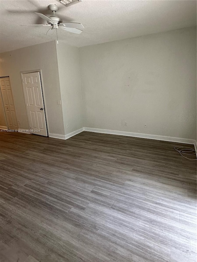 unfurnished room with a textured ceiling, ceiling fan, and dark wood-type flooring