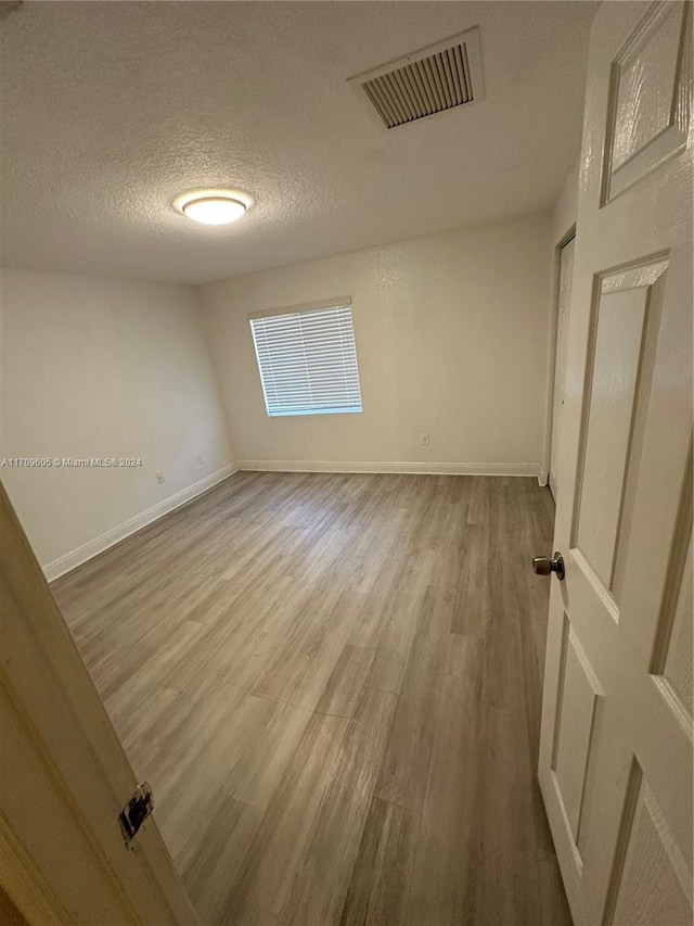 empty room featuring hardwood / wood-style flooring and a textured ceiling