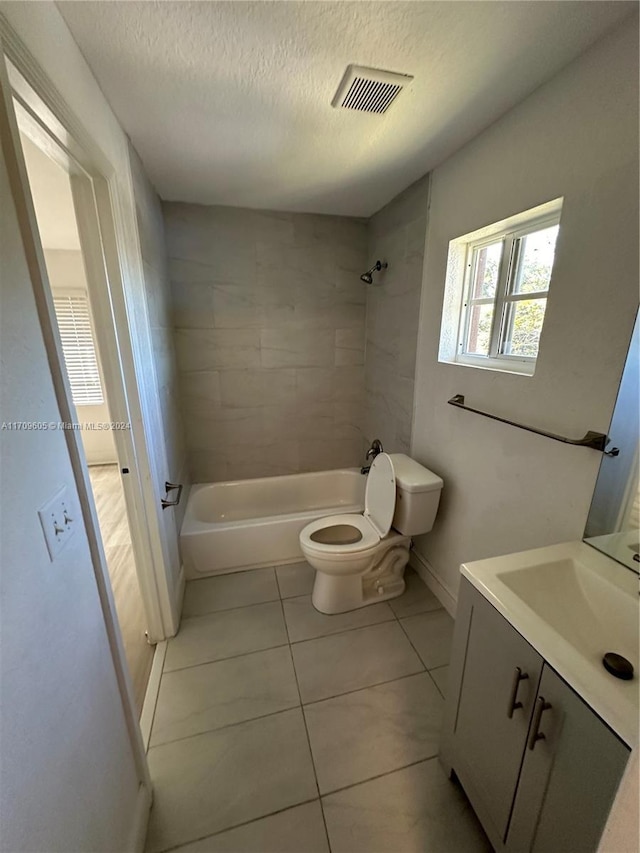 full bathroom featuring tiled shower / bath combo, tile patterned flooring, a textured ceiling, toilet, and vanity