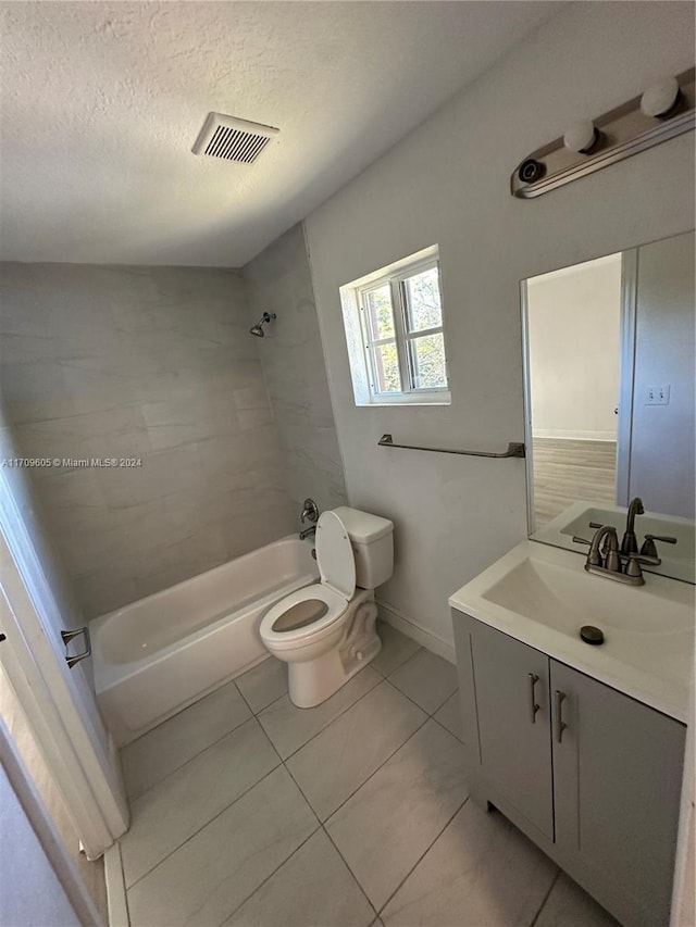 full bathroom featuring vanity, tile patterned floors, tiled shower / bath combo, toilet, and a textured ceiling