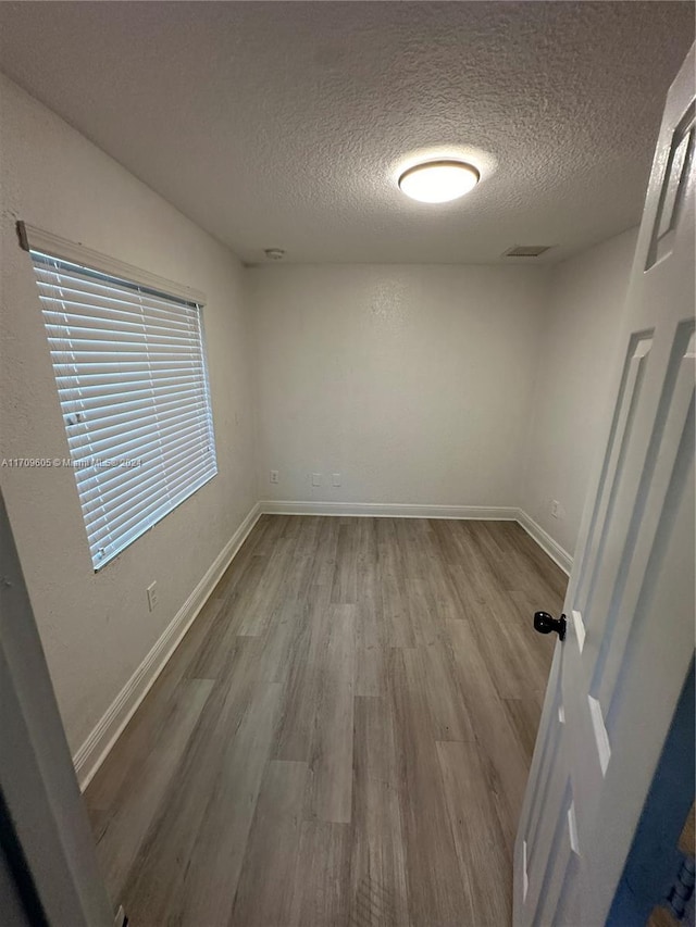 spare room with a textured ceiling and light hardwood / wood-style flooring