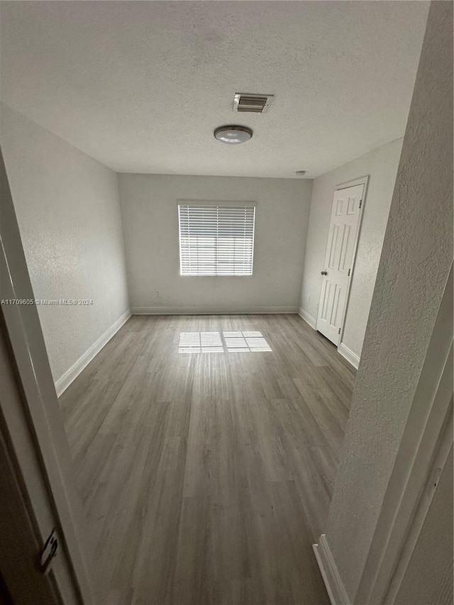 unfurnished room featuring hardwood / wood-style floors and a textured ceiling