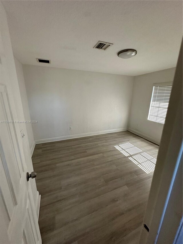 empty room with dark hardwood / wood-style floors and a textured ceiling