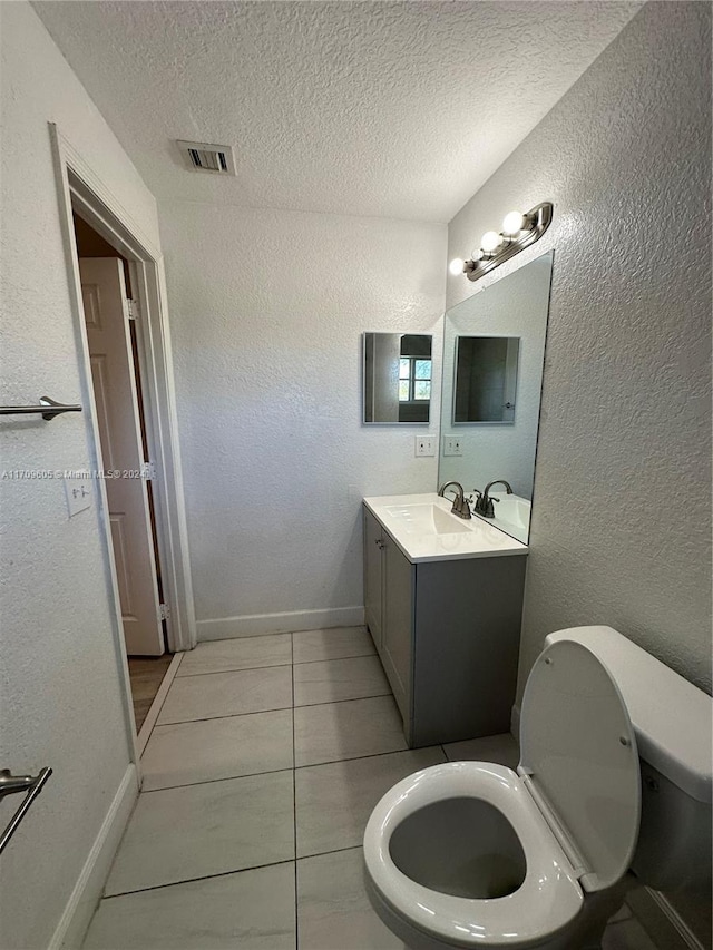 bathroom with tile patterned flooring, vanity, toilet, and a textured ceiling