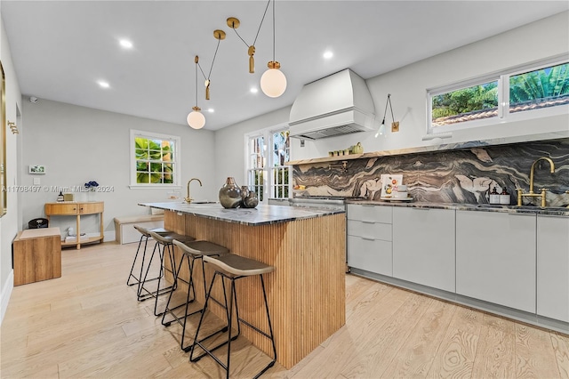 kitchen with premium range hood, white cabinetry, and a healthy amount of sunlight