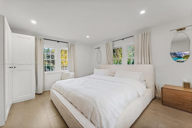 bedroom with light hardwood / wood-style floors and multiple windows