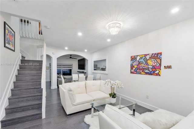 living room featuring ceiling fan with notable chandelier and dark wood-type flooring