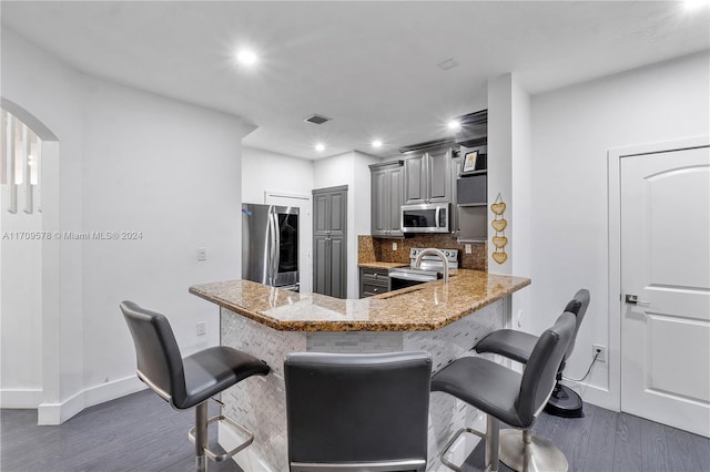 10307 SW 20th St, Miramar, FL 33025 - kitchen featuring appliances with stainless steel finishes, wood finished floors, arched walkways, a breakfast bar area, and recessed lighting