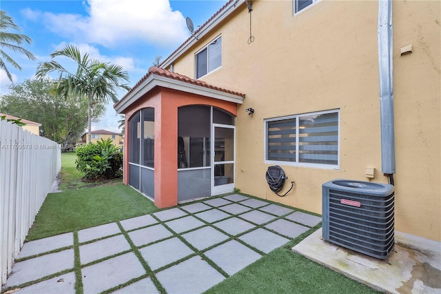 back of house featuring a patio area, a sunroom, a yard, and central AC unit