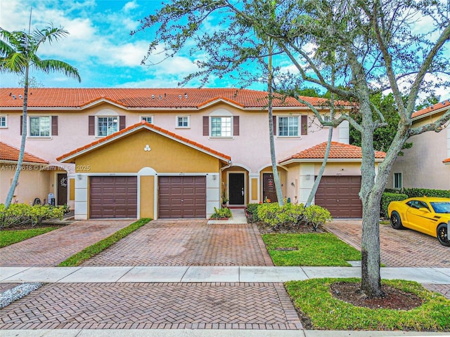 townhome / multi-family property with stucco siding, driveway, and a tiled roof