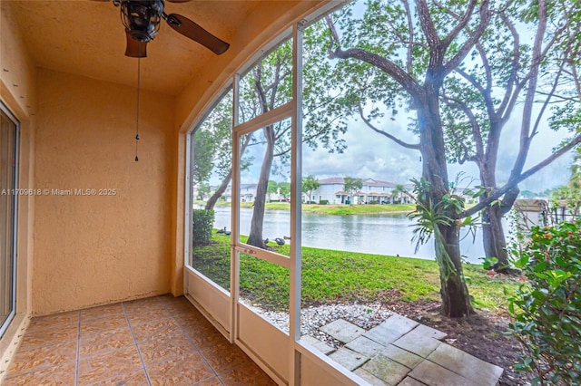 unfurnished sunroom with a ceiling fan, a water view, and a wealth of natural light