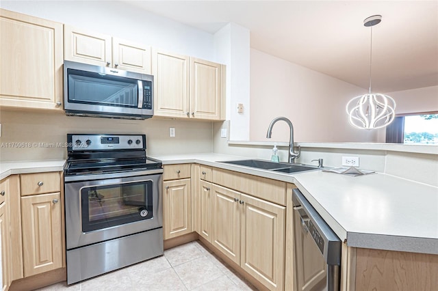 kitchen with light brown cabinets, a peninsula, a sink, stainless steel appliances, and light countertops