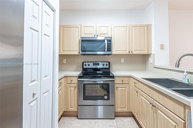 kitchen featuring a sink, stainless steel appliances, light tile patterned flooring, and light brown cabinetry