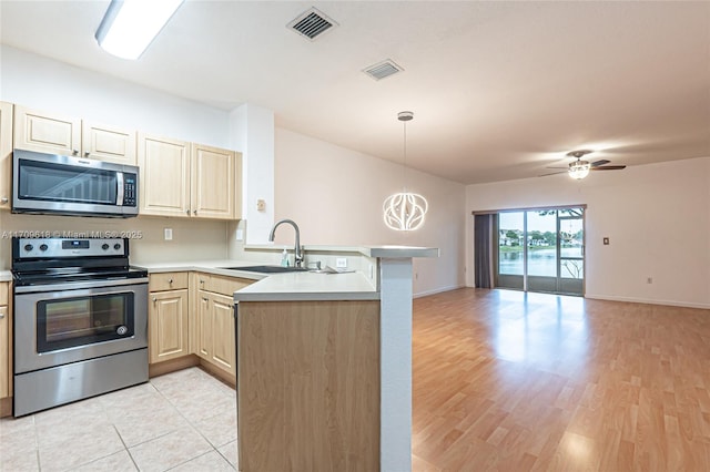 kitchen featuring visible vents, a sink, open floor plan, appliances with stainless steel finishes, and a peninsula