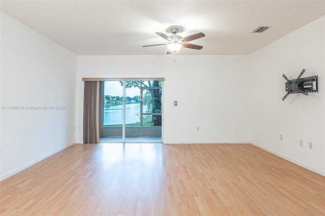 spare room featuring a ceiling fan, light wood-style floors, visible vents, and baseboards