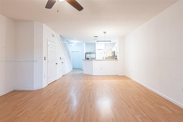 unfurnished living room featuring baseboards, light wood-style floors, and a ceiling fan