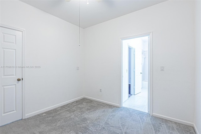 spare room featuring baseboards, light carpet, and a ceiling fan