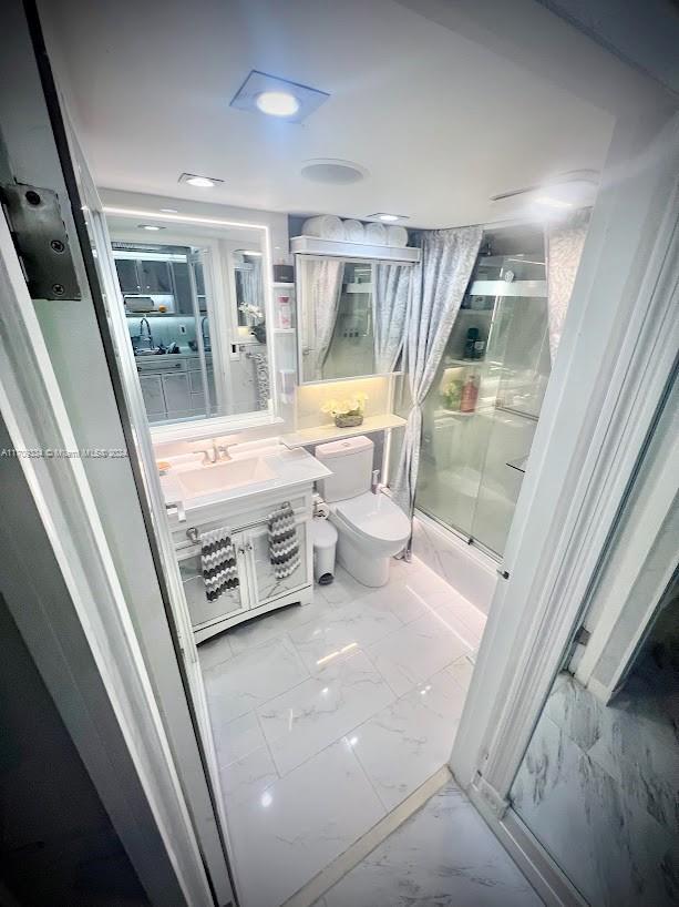 full bathroom with vanity, toilet, and bath / shower combo with glass door