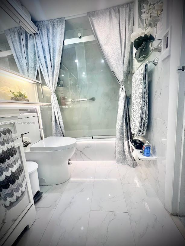 bathroom with toilet and a shower with door