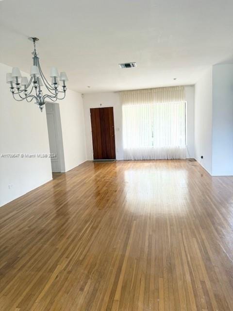 spare room featuring a notable chandelier and wood-type flooring