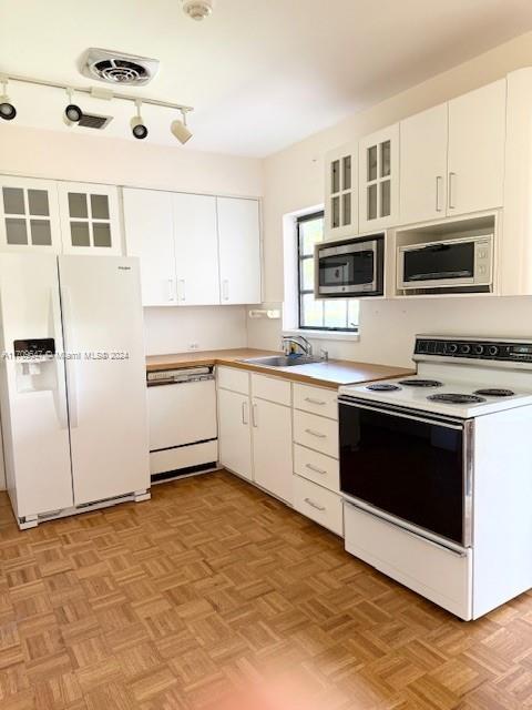 kitchen with white cabinets, white appliances, sink, and light parquet flooring