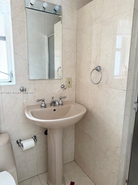 bathroom featuring a shower with door, toilet, and tile walls