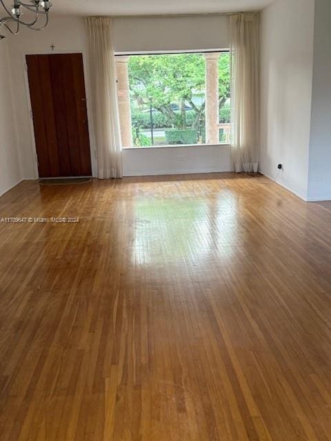 spare room with hardwood / wood-style flooring and an inviting chandelier