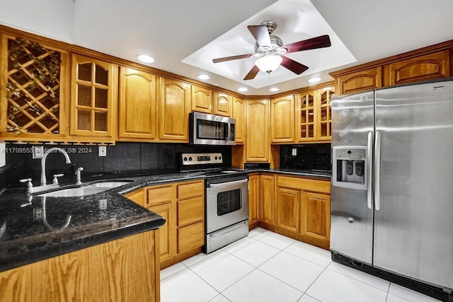 kitchen featuring tasteful backsplash, dark stone counters, stainless steel appliances, sink, and light tile patterned floors