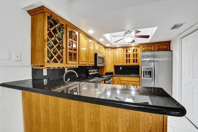 kitchen featuring decorative backsplash, kitchen peninsula, stainless steel appliances, and a skylight