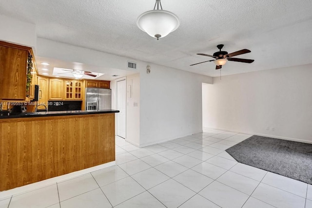 kitchen with decorative light fixtures, stainless steel fridge, light tile patterned flooring, and kitchen peninsula