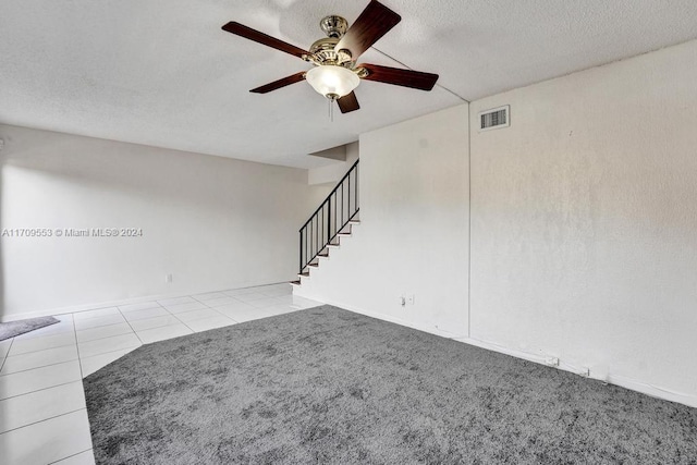 empty room featuring light tile patterned floors, a textured ceiling, and ceiling fan