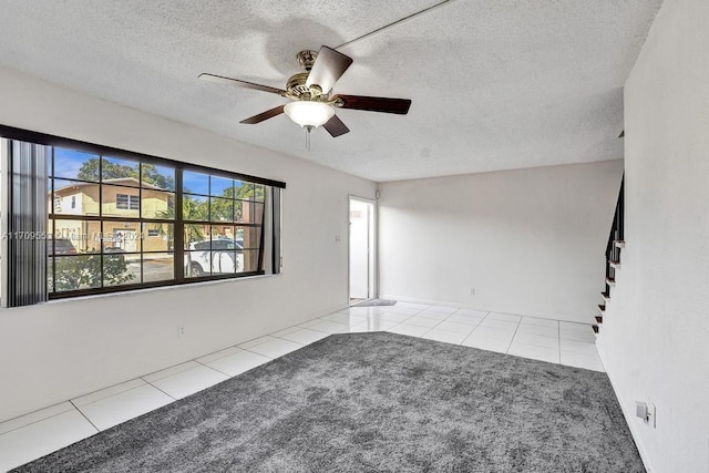 unfurnished room with ceiling fan, light tile patterned flooring, and a textured ceiling