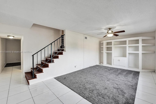 unfurnished living room with tile patterned floors, ceiling fan, and a textured ceiling