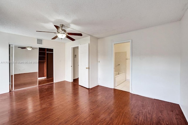 unfurnished bedroom featuring wood-type flooring, a textured ceiling, a closet, and ceiling fan